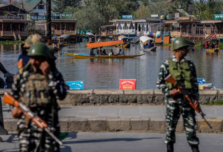 Indian paramilitary soldiers guard as tourists pass in a boat 