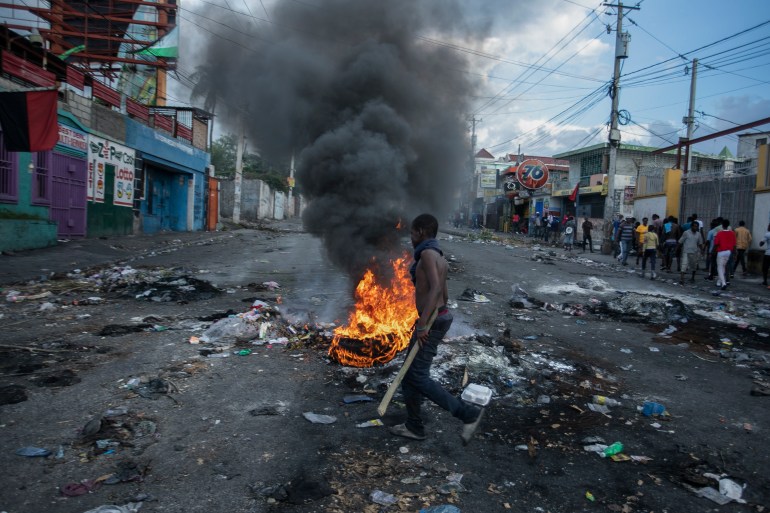 A man walks past burning tires in POrt-au-Prince Haiti