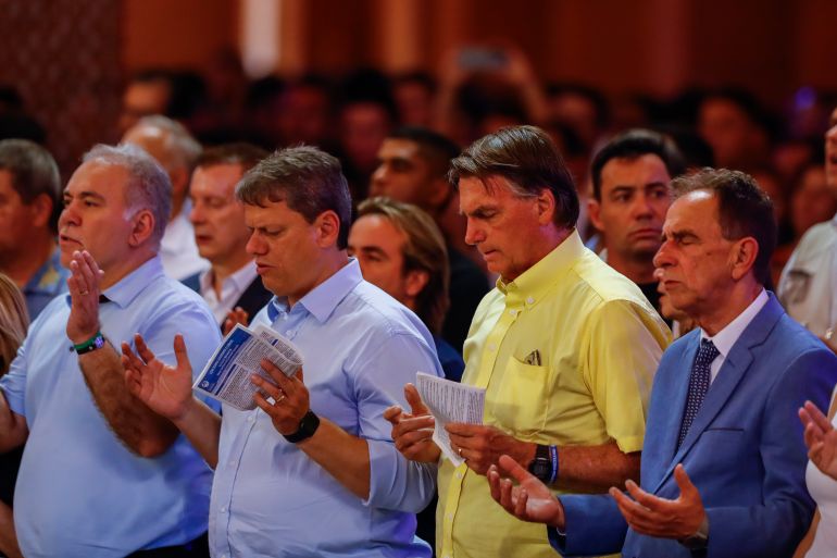 Brazil's President Jair Bolsonaro, second right, who running for reelection, and Sao Paulo candidate for governor Tarcisio de Freitas, center left, attend a Mass at the National Sanctuary of Our Lady Aparecida on her feast day in Aparecida, Sao Paulo state, Brazil, Wednesday, Oct. 12, 2022. Bolsonaro will face Luiz Inacio "Lula" da Silva in a presidential runoff on Oct. 30. (AP Photo/Marcelo Chello)
