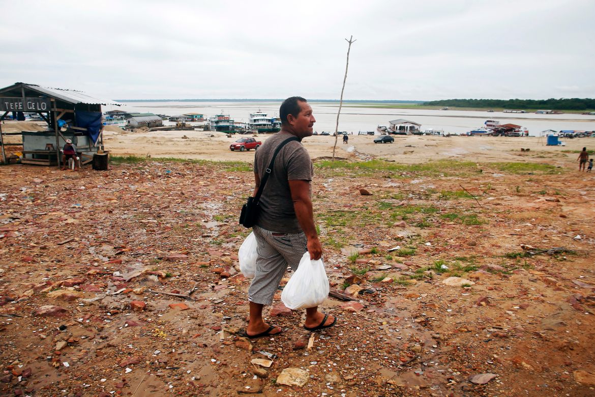 Pedro Canizio da Silva walks with food in an area impacted by the drought near the Solimões River, in Tefe, Amazonas state, Brazil