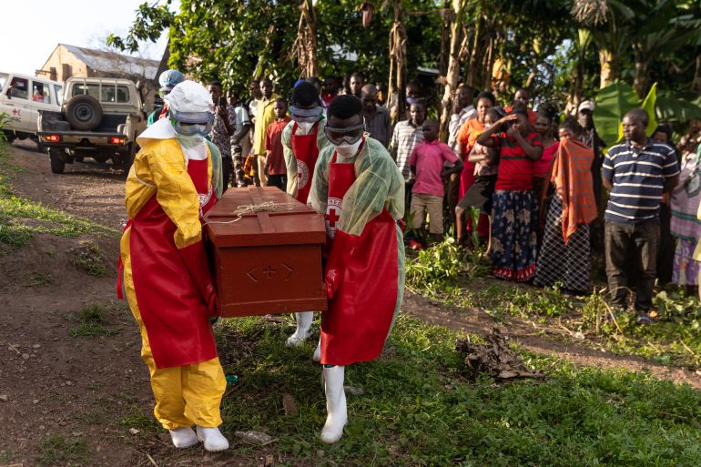 Ugandan Red Cross workers carry a coffin containing an Ebola victim during a Safe and Dignified Burial