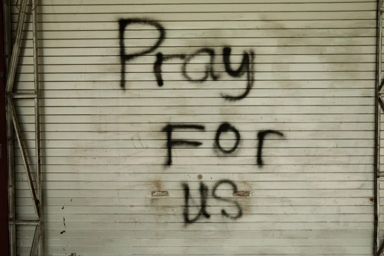 The words 'pray for us' sprayed in black onto a roller shutter in the Malang stadium where 125 people died in a crush