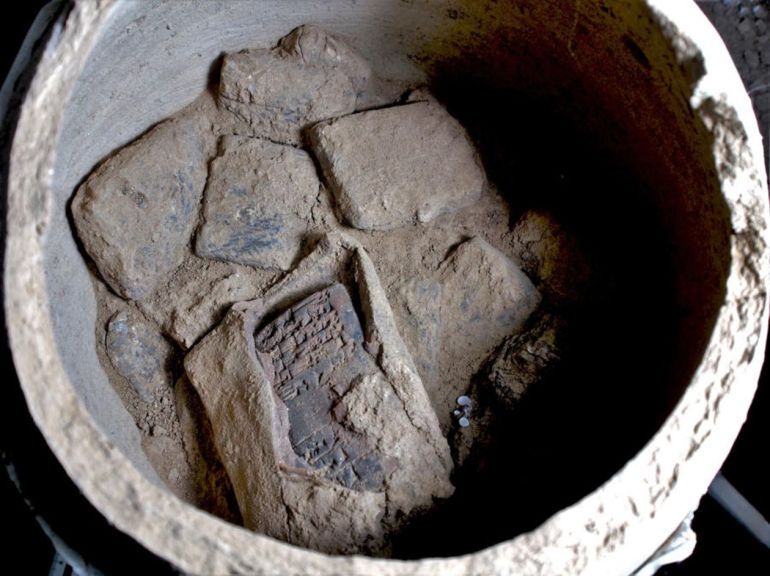 A photo of a view into one of the pottery vessels with cuneiform tablets, including one tablet which is still in its original clay envelope.