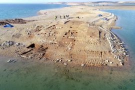 A photo of an aerial view of the excavations at Kemune with Bronze Age architecture partly submerged in the lake.