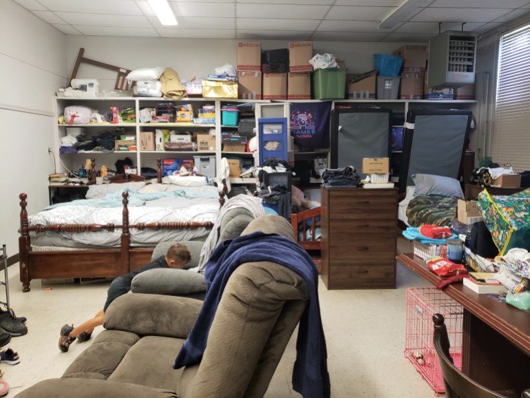 A room is filled with the beds and belongings of a family with two children and a puppy in Louisiana