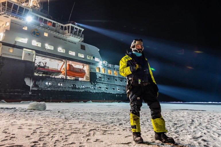 A researcher takes a standing guard for polar bears to protect the others as they work on the sea ice during a research expedition in the northern Barents sea.