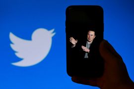 (FILES) In this file photo taken on October 4, 2022, a phone screen displays a photo of Elon Musk with the Twitter logo shown in the background, in Washington, DC. - Twitter said it will start laying off employees on November 4, 2022, as the new billionaire owner Elon Musk moves quickly after his big takeover to make the messaging platform financially sound