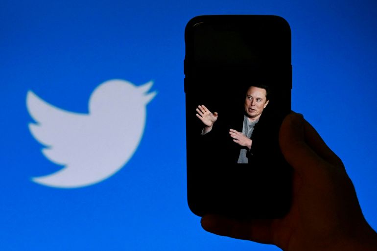(FILES) In this file photo taken on October 4, 2022, a phone screen displays a photo of Elon Musk with the Twitter logo shown in the background, in Washington, DC. - Twitter said it will start laying off employees on November 4, 2022, as the new billionaire owner Elon Musk moves quickly after his big takeover to make the messaging platform financially sound