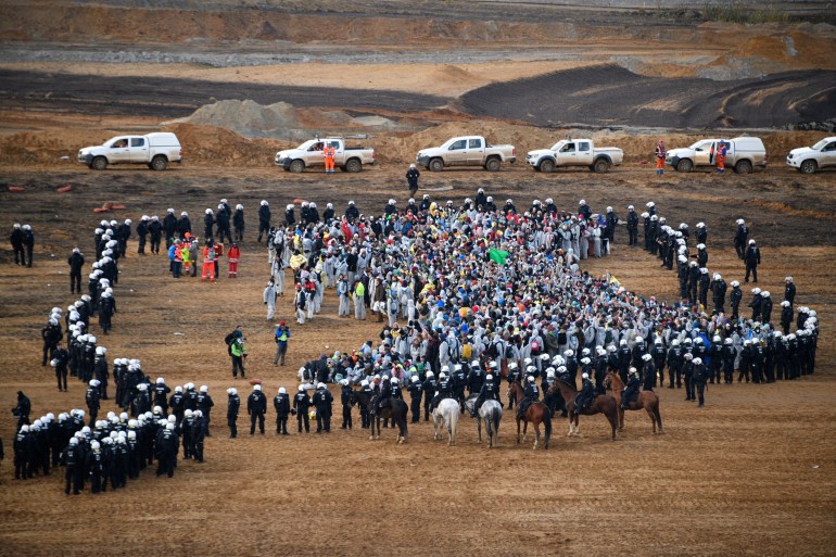 Policemen encircle environmentalists who managed to enter the Hambach lignite open pit mine near Elsdorf, western Germany, on November 5, 2017, during a protest against fossil-based energies like coal. according to the organisers.