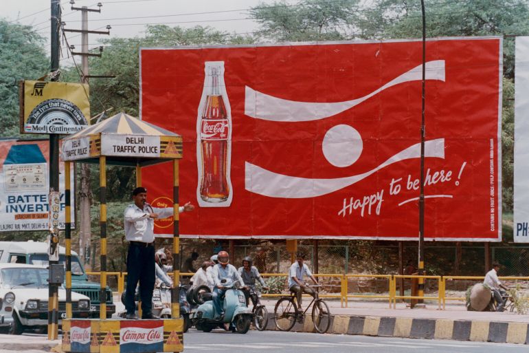 A traffic policeman directs traffic at a busy junction in front of a billboard for a new Coca-Cola advertising campaign in New Delhi.