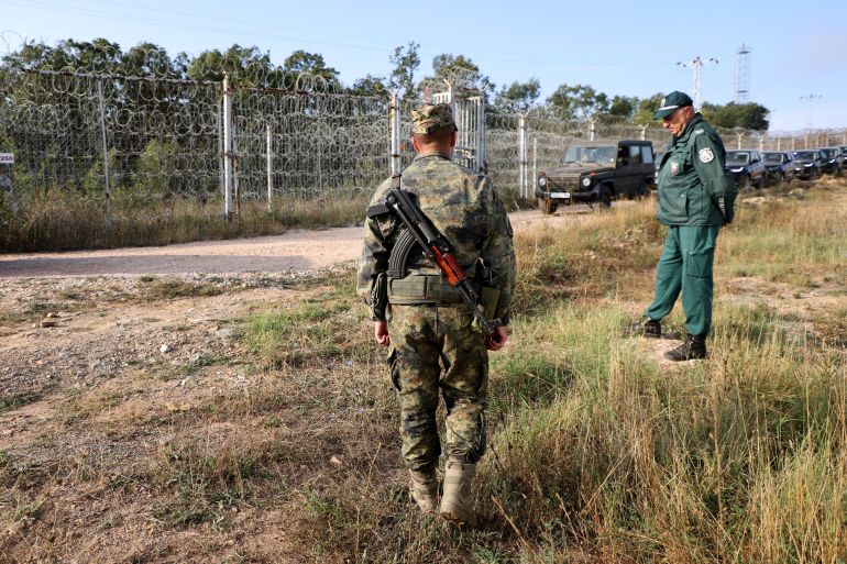 Bulgarian border police personnel stand near the fence, built across the Bulgarian-Turkish border, near Elhovo, Bulgaria