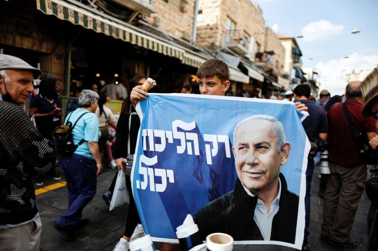 A supporter of former Israeli Prime Minister Benjamin Netanyahu holds up an election banner as he campaigns at Mahane,Yehuda market Jerusalem
