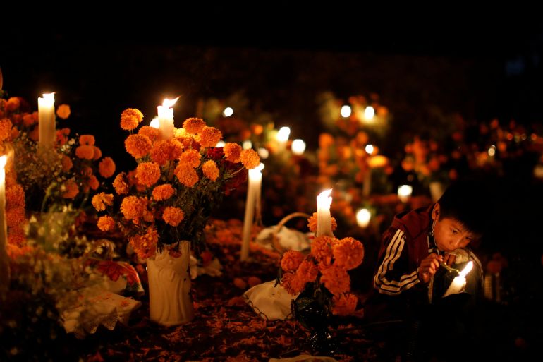 A boy plays with a candle during the Day of the Dead at a cemetery in the Purepecha indigenous community of Cucuchuchu, Michoacan state, Mexico November 2, 2022. REUTERS/Raquel Cunha