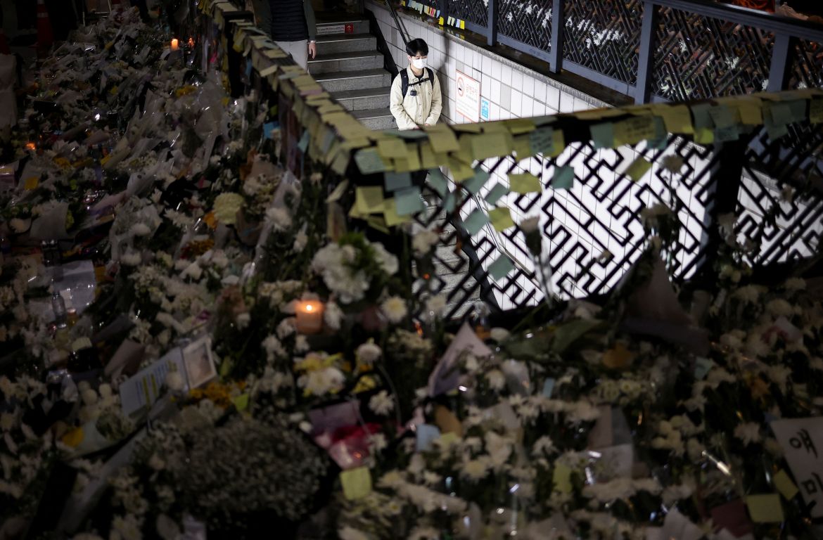 A mourner walks near floral tributes, near the site of a crowd crush.