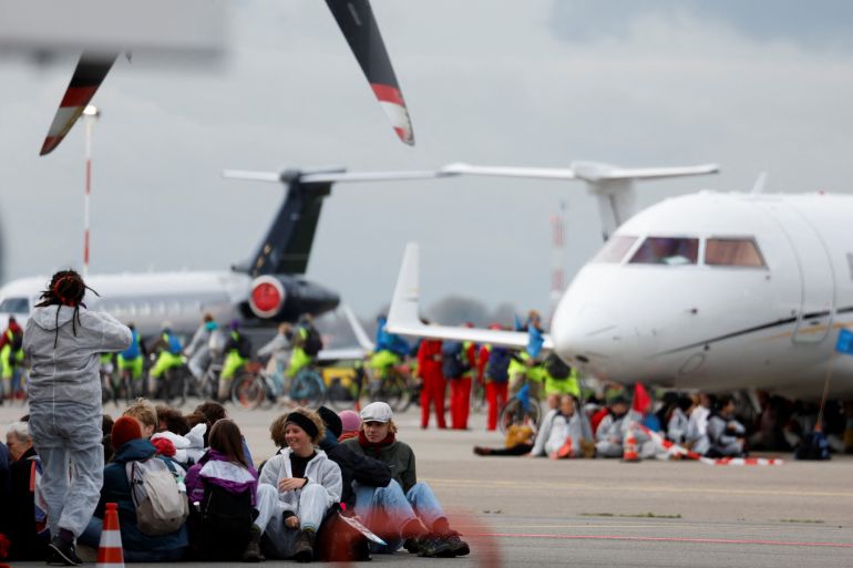 Climate activists sitting on the tarmac in front of private jets at Schipol Airport.