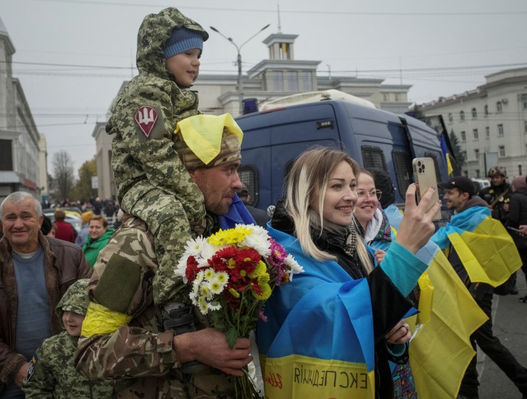 Local residents take a photo with Ukrainian serviceman as they celebrate after Russia's retreat from Kherson, in central Kherson, Ukraine 