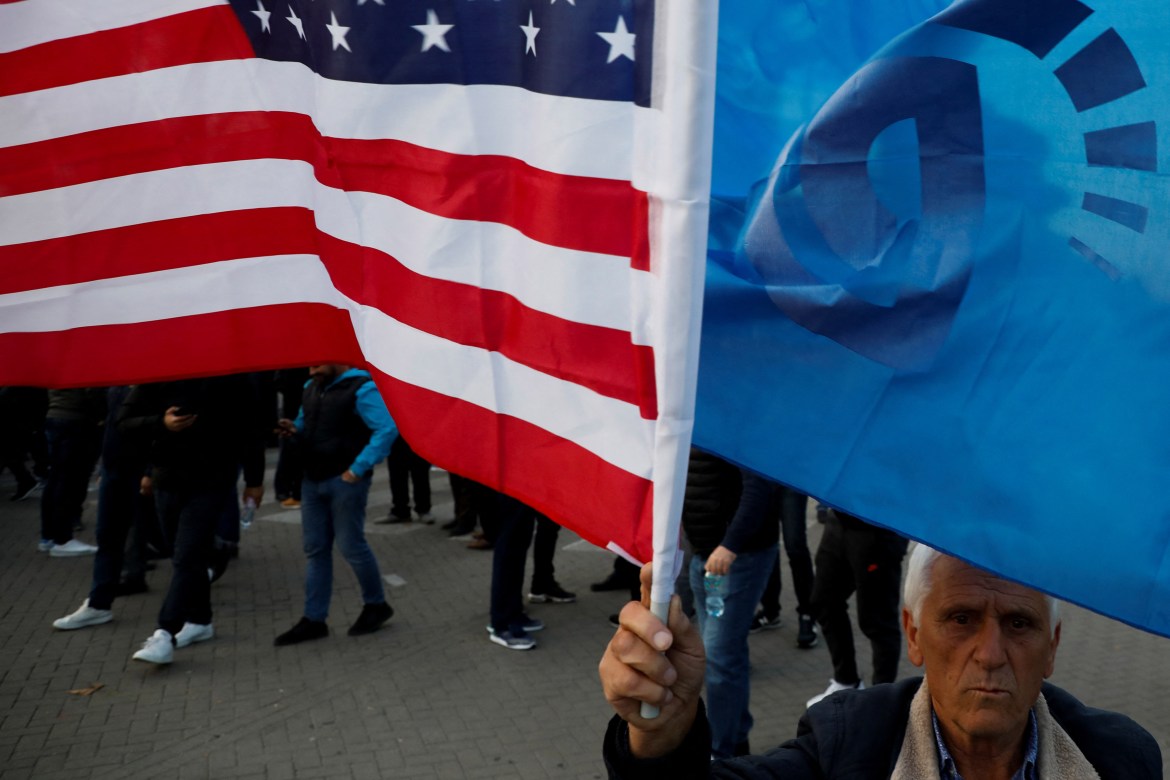 A man holds U.S. flag and Democratic Party flag.