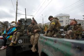 Ukrainian service members sit on cars