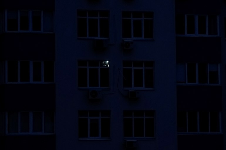 A man with a torch in the darkness of his flat in Kyiv, Ukraine.