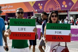 Iranians hold up posters in support of anti-government protests outside a stadium in Qatar