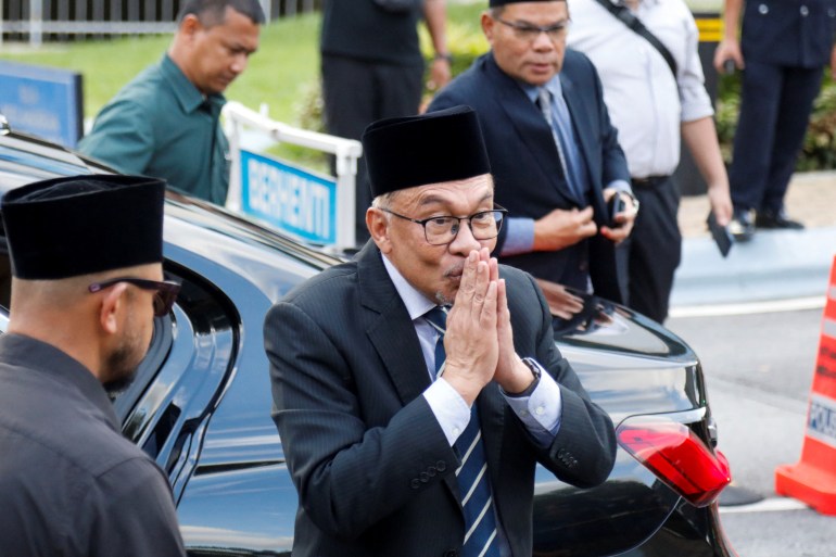 Anwar puts his hands together as he comes out of the palace to speak to reporters. He seems to be confident