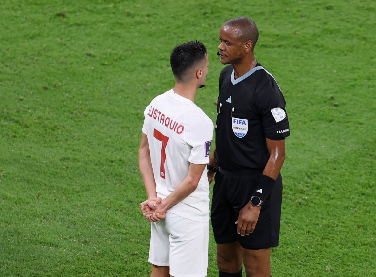Referee Janny Sikazwe and Canada's Stephen Eustaquio react to each other face to face at a close distance.