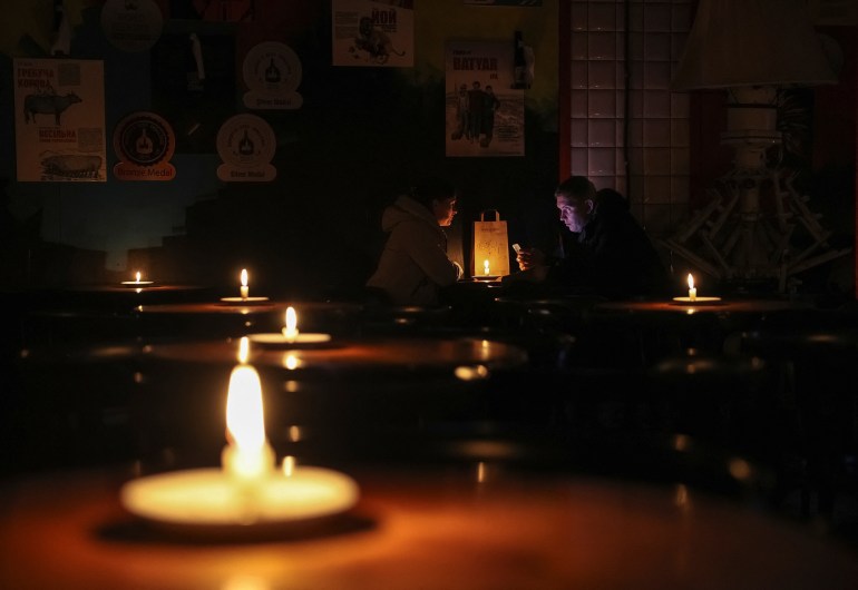 People sit in a pub lit with candles during a power outage in Lviv.
