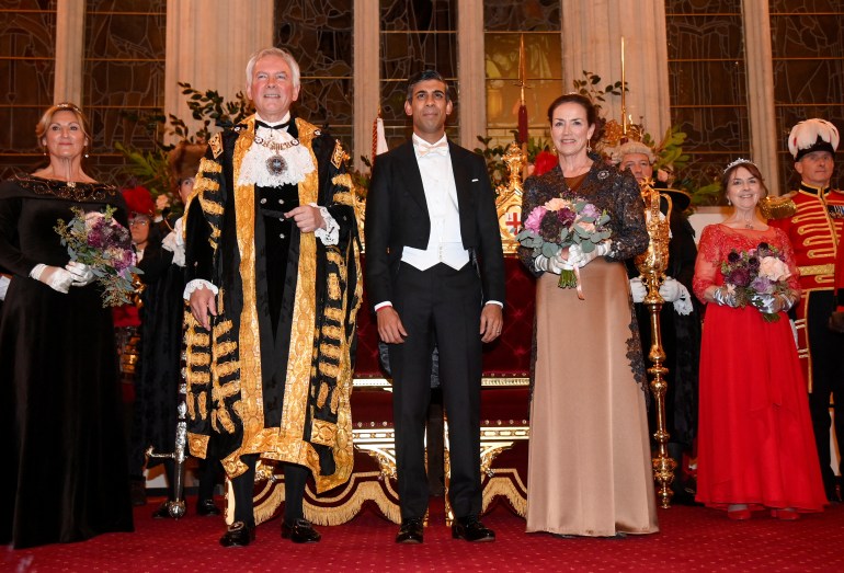 Rish Sunak in evening white tie stands between an ornately robed Lord Mayor of the City of London and the mayor's wife at the Guildhall