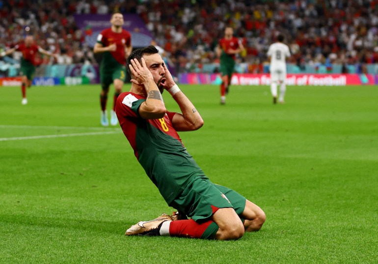 Portugal's Bruno Fernandes, kneeling on the pitch, celebrates scoring their second goal.