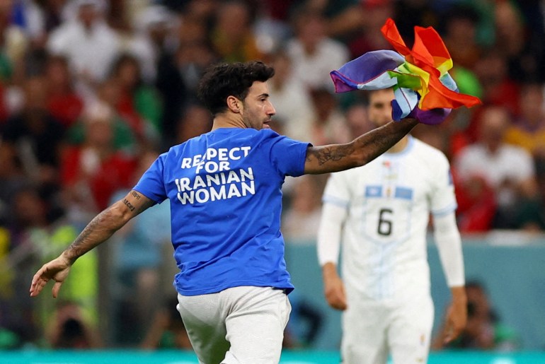 A pitch invader runs onto the field wearing a 'Respect for Iranian woman' shirt and holding a rainbow flag during the Portugal vs Uruguay game at Lusail Stadium, Lusail, Qatar.