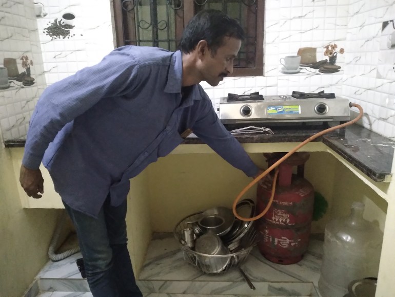 A man connects a gas cylinder to a stove