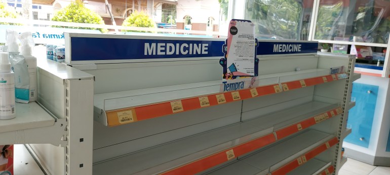 Empty shelves in a pharmacy with a sign telling customers that cough syrups have been removed from sale
