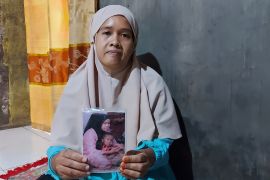 Siti sits in her house holding a picture showing her with her five year old son Mohammad Fajar