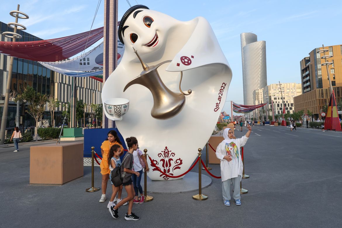 A girl poses in front of Qatar 2022 mascot La'eeb in Lusail ahead of the Qatar 2022 FIFA World Cup football tournament.