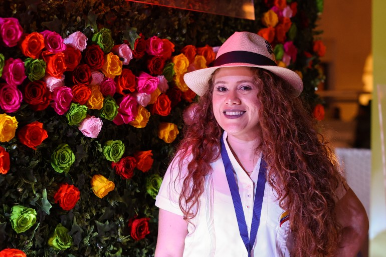 Judith from Ecuador poses in front of a wall of flowers