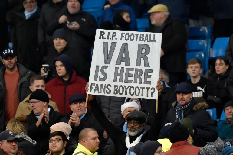 A fan holds up a banner against Video Assistant Referee (VAR) during the English Premier League soccer match between Manchester City and Everton at Etihad stadium in Manchester, England, Wednesday, Jan. 1, 2020.