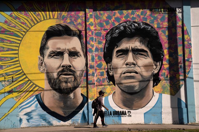 A pedestrian walks past a mural depicting soccer legends Lionel Messi and Diego Maradona, in Buenos Aires, Argentina, Tuesday, Nov. 1, 2022. (AP Photo/Rodrigo Abd)