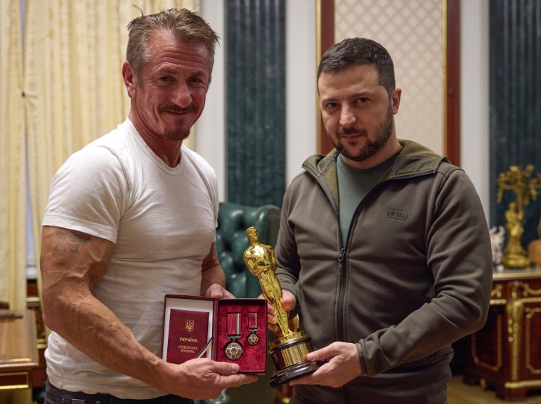 Ukrainian President Volodymyr Zelenskyy holding an Oscar's statuette poses with American actor Sean Penn who is holding a medal of the Order of Merit.
