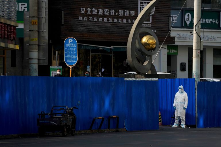 China worker in protective gear watches residents in face masks