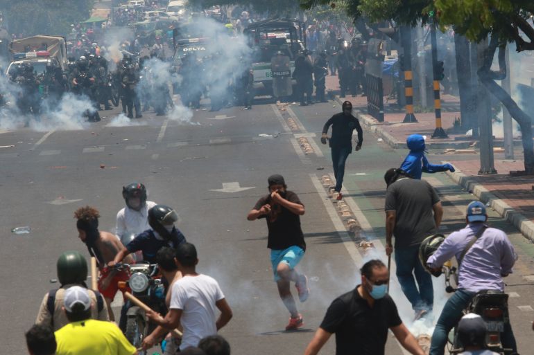 A line of police advances in a street in Santa Cruz, Bolivia, where tear gas has been used to disperse protesters