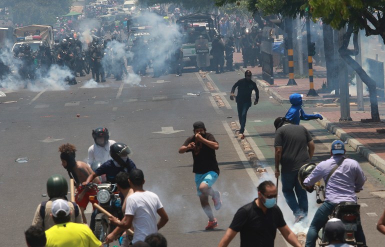 A line of police advances in a street in Santa Cruz, Bolivia, where tear gas has been used to disperse protesters
