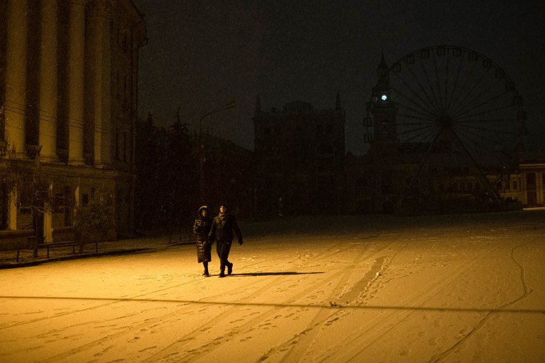 Two people walk in the dark because of power cuts on a snow covered Kyiv street
