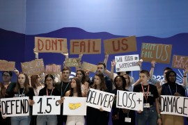 Youth activists hold signs encouraging world leaders to maintain policies that limit warming to 1.5 degrees Celsius since pre-industrial times
