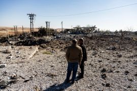 Two men inspect airstrike damage in Syria