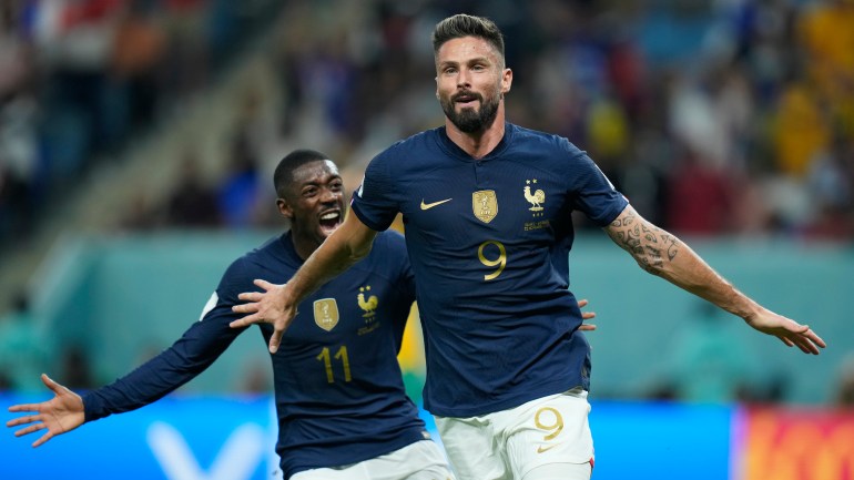 Giroud runs with his arms out as Dembele comes up behind him, smiling