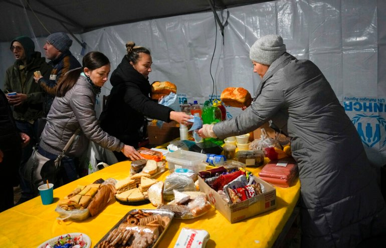 A volunteer distributes free food to people who lost electrical power after recent Russian attacks, in a heating point in the town of Vyshhorod, north of Kyiv, Ukraine, Friday, Nov. 25, 2022. (AP Photo/Efrem Lukatsky)