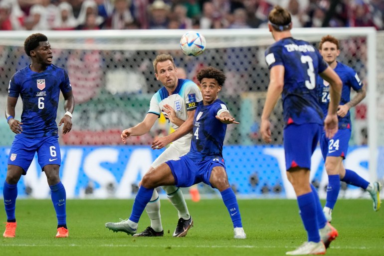 England's Harry Kane, center left, vies for the ball with Tyler Adams of the United States during the World Cup group B soccer match