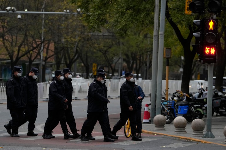 Police walking across a street, with barriers behind, at a Beijing junction where a protest had been held the day before.