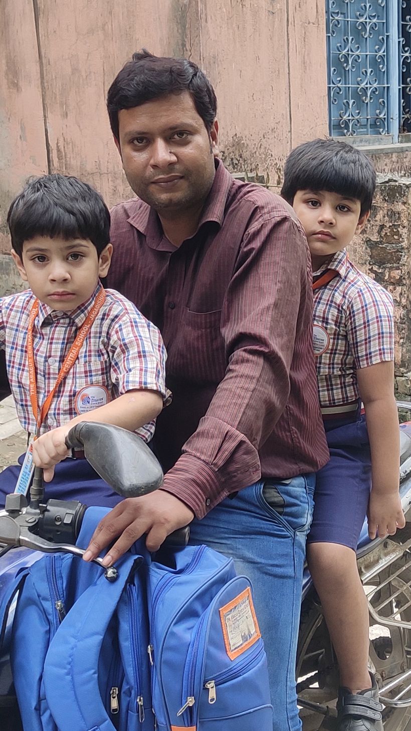 A photo of Arijit Khan with his two children, one in front and one behind him on a motorcycle.