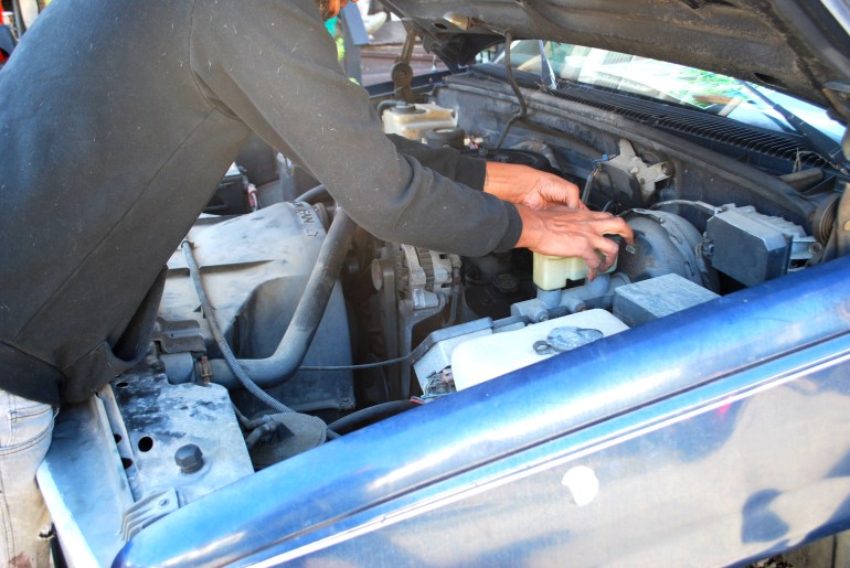 A photo of Aman checking the brake fluid in a truck.